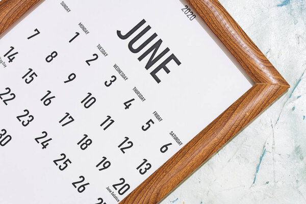 June 2020 monthly calendar placed in the wooden picture frame. View from above