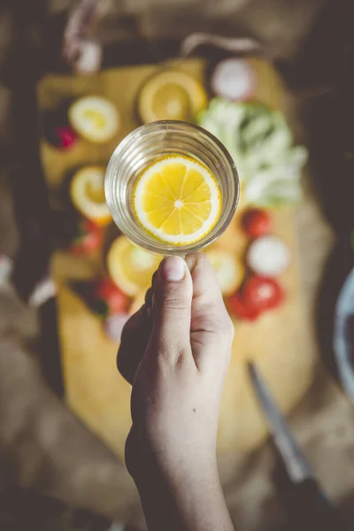 一个无法辨认的女人手拿着一杯清水和一片柠檬 有机和健康食品的概念 从上面看 — 图库照片