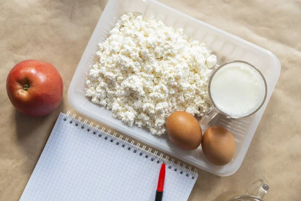Diet planning. Meal plan - healthy food: Fresh water, cottage cheese and empty notepad