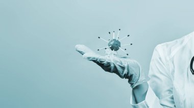 Korunaklı tıbbi üniformalı kadın doktor elinde koronavirüs tutuyor. Yeni Coronavirus veya COVID-19 'un el yapımı modelini elinde tutan bilim adamı virolog.