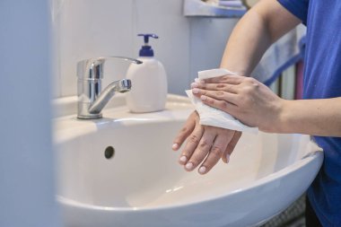 Kadının banyo musluğunun altında sabun kullandığı ve ellerini yıkadığı yakın çekim görüntüsü. Koronavirüs salgınını durdurmak için kişisel temizlik.