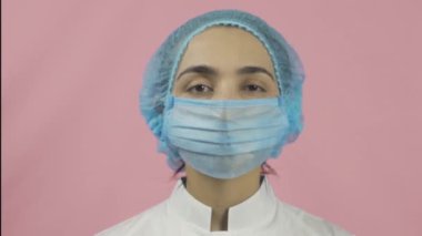 Tıbbi maske takan kadın doktor kameraya bakıyor. Bilim adamı ya da virolog. Sağlık hizmetleri çalışanı. Covid 19