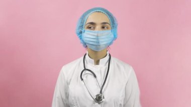 Tıbbi maske takan kadın doktor kameraya bakıyor. Bilim adamı ya da virolog. Sağlık hizmetleri çalışanı. Covid 19