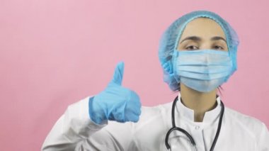 Tıbbi maske takan kadın doktor ve tıbbi eldivenler el hareketini onaylıyor. Merak etme, mutlu ol. Covid-19 'dan ya da salgın sonrası dönemden sonra. Coronavirus 'a karşı zaferi kutluyoruz.