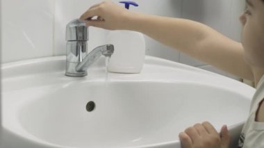 Küçük bir çocuk ellerini yıkıyor. 7 yaşındaki çocuk ellerini yıkıyor.