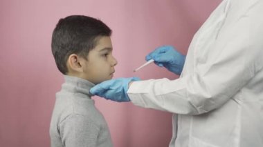 Anaokulu çocuğunun boğazını kontrol eden kadın doktor.