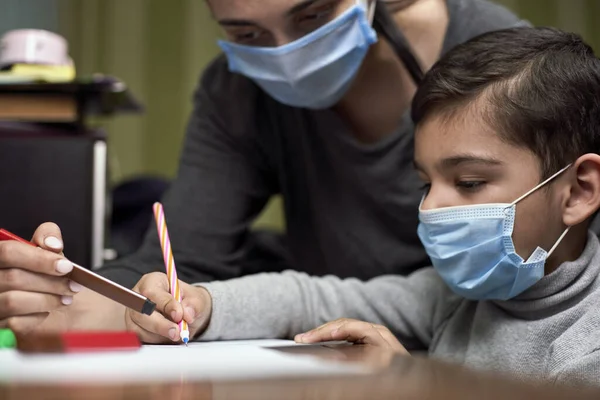 Uzaktan eğitim. Annesi anaokulu öğrencisinin ders almasına yardım ediyor. Karantina zamanında eğitim. Koronavirüs salgını sırasında çocukların korunması