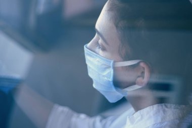 Coronavirus salgını sırasında araba süren cerrahi maske ve eldivenli genç bir kadın. Koruyucu giysili bir kadın sürücü, covid-19 virüsünü önlüyor.