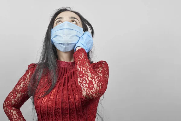 Gece elbisesi ve cerrahi maske takan genç bir orta doğulu kadın. Cerrahi maskeli güzel kadın kutlama yapıyor. Karantina sırasında covid-19 salgınına karşı eğlenen orta yaşlı kadın portresi
