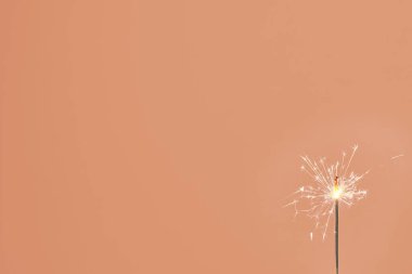 Turuncu arka planda yalnız bir maytap. Kutlama, tatil, doğum günü, yıldönümü, yeni yıl, Noel kavramları