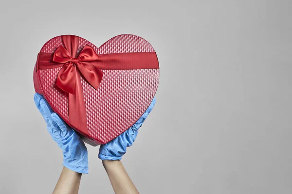 Celebrating birthday. A love story in the hospital. Nurse receiving a heart-shaped present box. Self-isolation, social distancing, and love talks with gifts in quarantine during the covid-19 pandemic