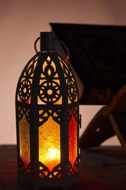 Karanlık ve kutsal Kur 'an' da parlayan yanan mumlarla süslenmiş Arapça bir fener. Kutlama kartı, Müslüman kutsal ayı için davetiye Ramazan Kareem