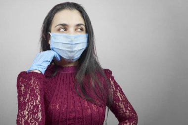 Gece elbisesi ve cerrahi maske takan genç bir orta doğulu kadın. Cerrahi maskeli güzel kadın kutlama yapıyor. Karantina sırasında covid-19 salgınına karşı eğlenen orta yaşlı kadın portresi