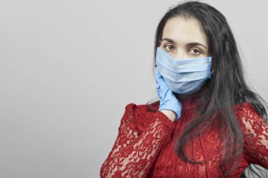 Gece elbisesi ve cerrahi maske takan genç bir orta doğulu kadın. Cerrahi maskeli güzel kadın kutlama yapıyor. Karantina sırasında covid-19 salgınına karşı eğlenen orta yaşlı kadın portresi