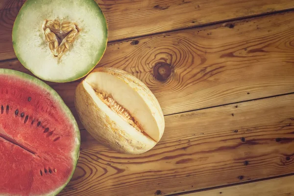 Sweet organic summer muskmelons and watermelon on the wooden background. Ripe melons on wood. View from above. Top view. Copy space