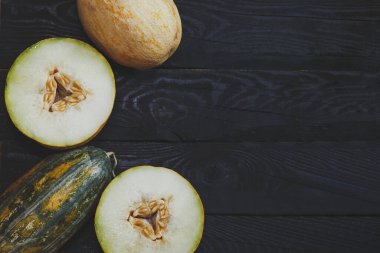 Koyu ahşap arka planda tatlı organik yaz kavunları. Tahtada dilimlenmiş olgun kavun. Yukarıdan bak. Üst Manzara. Boşluğu kopyala