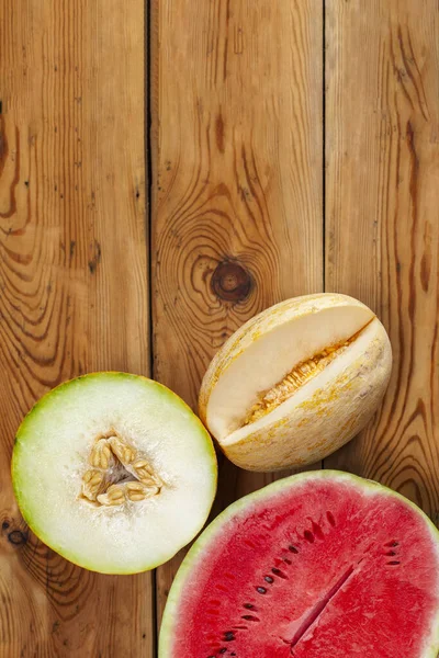 Sweet organic summer muskmelons and watermelon on the wooden background. Ripe melons on wood. View from above. Top view. Copy space