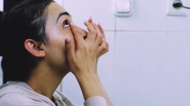 Banyoda makyaj maskesi takan bir kadın. Karışık ırk dişileri yüzüne beyaz besleyici maske ya da krem sürerler. Yüzüne maske takıyorum. Cilt temizleme spa rahatlama konsepti