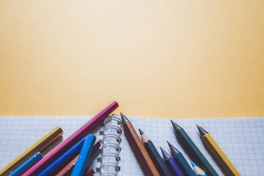 Okul malzemeleri sarı üzerine. Okul geçmişine geri dönelim. Not defteri ve renkli kalemler yığını. Uzaklık eğitimi, karantina eğitimi, ev kavramlarından öğrenme ve öğrenme