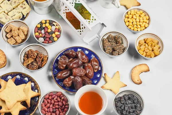 Traditional Ramadan dinner on pure white table. Traditional middle-eastern lunch with cookies and sweets. Ramazan Iftar food - meal Muslims eat after sunset during Ramadan. Top view