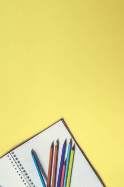 Okul malzemeleri sarı üzerine. Okul geçmişine geri dönelim. Not defteri ve renkli kalemler yığını. Uzaklık eğitimi, karantina eğitimi, ev kavramlarından öğrenme ve öğrenme