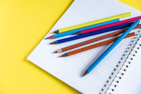 School supplies on yellow. Bright back to school background. Notepad and stack of colorful pencils. Distance education, Education in quarantine, Studying and learning from home concepts