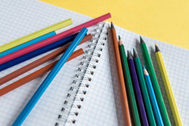 Okul malzemeleri sarı üzerine. Okul geçmişine geri dönelim. Not defteri ve renkli kalemler yığını. Uzaklık eğitimi, karantina eğitimi, ev kavramlarından öğrenme ve öğrenme