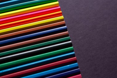 Karanlık arka planda okul malzemeleri. Okul geçmişine dönelim. Not defteri ve renkli kalemler yığını. Uzaklık eğitimi, karantina eğitimi, ev kavramlarından öğrenme ve öğrenme