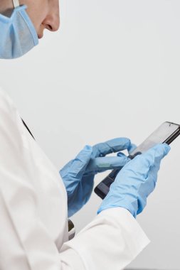 Mola sırasında cep telefonu kullanan kadın doktor. İnternet taranıyor, haber, e-posta ve sohbet mesajları kontrol ediliyor