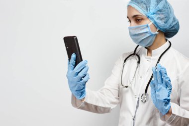 Koruyucu tıbbi teçhizat içinde, cep telefonu tutan bir sağlık çalışanı. Mola sırasında kadın doktor. Hemşire zoom video aracılığıyla ailesiyle konuşuyor.