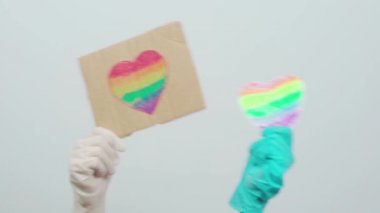 Gurur günü. LGBTQ dostu sağlık çalışanı elinde kalp şeklinde gökkuşağı bayrağı olan el yapımı bir pankart tutuyor. LGBTQ doktoru Coronavirüs 'e karşı cephede savaşıyor.