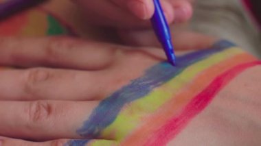 Gurur günü. Kadın el bileğine gökkuşağı bayrağı çiziyor. LGBTQ tarzı vücut sanatı. 2020 Onur Festivali. İnsan hakları, cinsiyet eşitliği kavramları