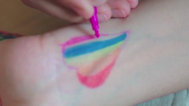 Gurur günü. Kadın el bileğine gökkuşağı bayrağı çiziyor. LGBTQ tarzı vücut sanatı. 2020 Onur Festivali. İnsan hakları, cinsiyet eşitliği kavramları