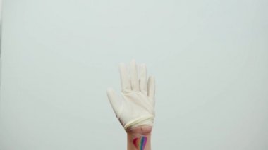 Lezbiyen hemşire cephede koronavirüsle savaşıyor. Bileğinde gökkuşağı bayrağı olan LGBTQ dostu sağlık çalışanı. LGBTQ dostu doktor ya da cerrahi eldiven giyen sağlık görevlisi