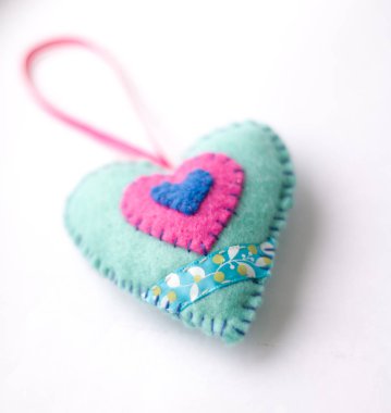 Beyaz arka planda keçeden yapılmış oyuncaklar, renkli kalp