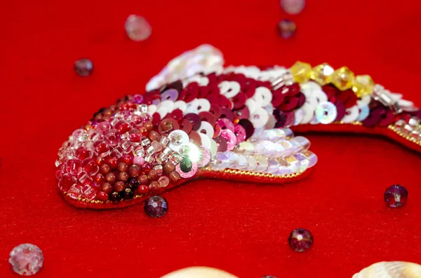 Koi fish from beads and sequins on a red background