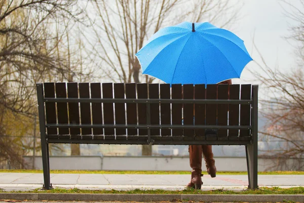 Mavi şemsiye bankta yağmurlu günde siting ile yalnız kız — Stok fotoğraf