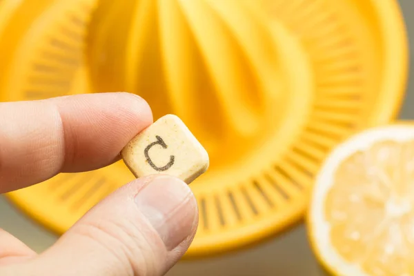 Comprimido de vitamina c entre os dedos e limão fresco — Fotografia de Stock