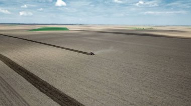 Tarlada kar küreyen kırmızı traktörün hava manzarası