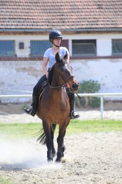 Binicilik okulunda miğferli ata binen kız.