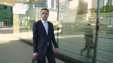 Bakarak işadamı caddeden aşağı yürüyüş takım elbiseli. Steadicam atış.