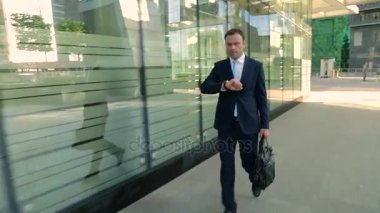 Acele, takım elbiseli Merhaba işadamıdır geç, bakarak. Steadicam atış.
