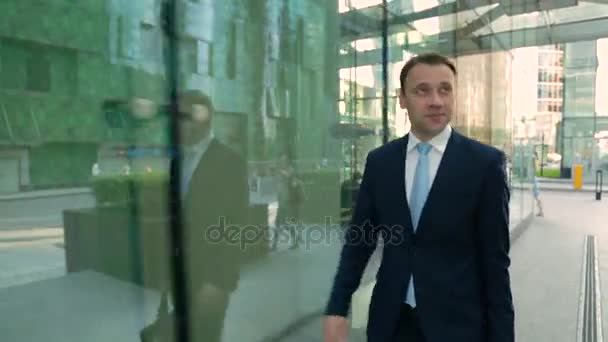 Felice uomo d'affari in giacca e cravatta che cammina per strada. Steadicam shot . — Video Stock