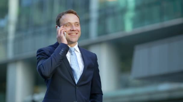 Привлекательный бизнесмен разговаривает по телефону в городе — стоковое видео
