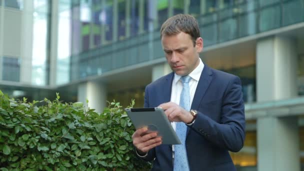 Przystojny biznesmen korzystający z tabletu na ulicy — Wideo stockowe