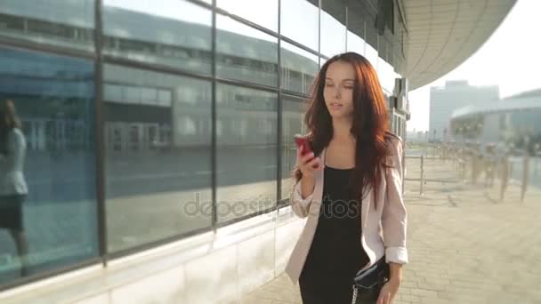 Hezká dívka chodí a mluví na telefonu na slunci. Steadicam shot. — Stock video