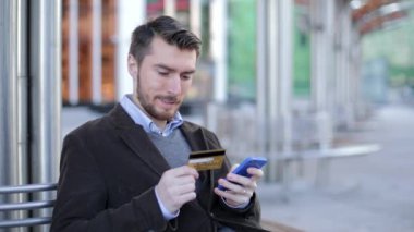 Çekici bir adam akıllı sokakta kredi kartı ile online banka kullanarak