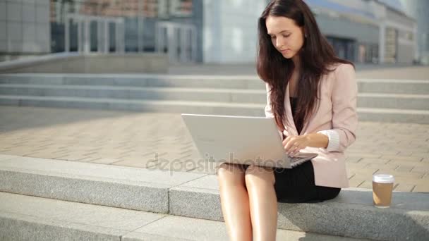 Сексуальная красотка, использует ноутбук на улице, усердно работает. — стоковое видео