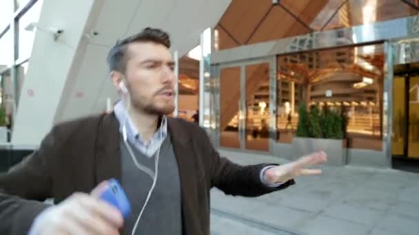 Jóképű férfi zenehallgatás fejhallgató smartphone, a járás és a tánc — Stock videók