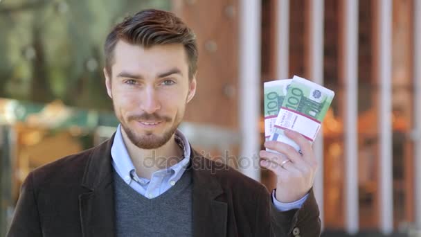 Feliz hombre atractivo sosteniendo en su mano paquetes de dinero en efectivo Euro — Vídeos de Stock